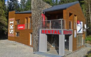 a wooden building with a rental return sign on it at Apartment Bartek Ski Rental in Demanovska Dolina