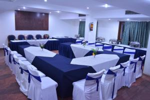 une salle de banquet avec des tables blanches et des chaises bleues et blanches dans l'établissement The Central Park Hotel, à Gwalior