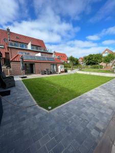 a large yard with a lawn in front of a building at Winkelschiffchen II mit Sauna in Juist