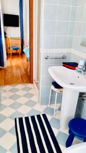 La salle de bains est pourvue d'un lavabo blanc et d'un sol bleu et blanc. dans l'établissement LILLI'S HOME Appartamento confortevole vicino ad Asiago, à Roana