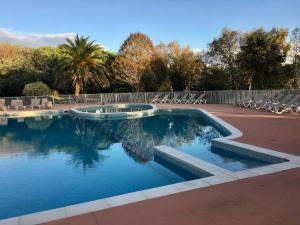 a swimming pool with chairs and trees and a fence at Appart Cosy Green, Océan, Golf, Piscine, Wifi in Moliets-et-Maa