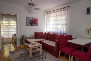 a living room with a red couch and red chairs at Apartments Oaza in Daruvar
