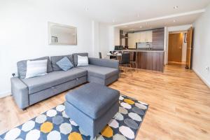 a living room with a gray couch and a kitchen at Liverpool St Shoreditch London Terrace Apartment in London