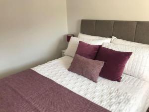 a bed with purple and white pillows on it at Almond Cottage Clare - 2 bedroom English Cottage in Clare