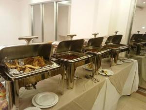 Una mesa larga con sillas y comida en bandejas. en Hotel Aristos Boutique & Suites, en Chittagong