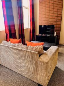 ein Wohnzimmer mit einem Sofa und einem TV in der Unterkunft The Gold Hut in Johannesburg