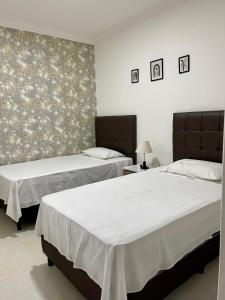 2 camas en una habitación con sábanas blancas en Edificio Las Palmas 3100, en Santa Cruz de la Sierra