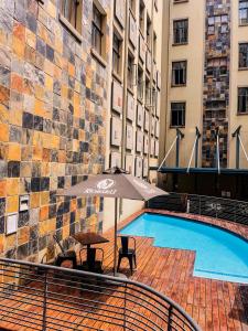 uma piscina com uma mesa e um guarda-sol ao lado de um edifício em The Gold Hut em Joanesburgo