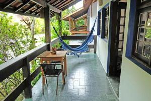a porch with a hammock and a table and chairs at Casa sossegada ao lado da natureza e do mar in São Sebastião