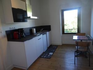 a kitchen with white cabinets and a table and a window at MAHE in Plancoët