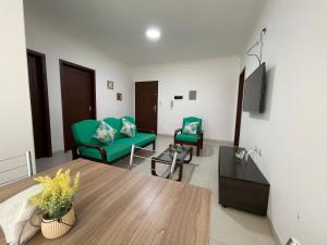 sala de estar con 2 sillas verdes y mesa en Edificio Las Palmas 3100, en Santa Cruz de la Sierra