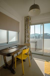 une salle à manger avec une table en bois et une chaise jaune dans l'établissement Departamento con vista a las montañas + garage, à Salta