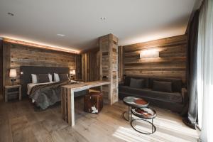 1 dormitorio con paredes de madera, 1 cama y escritorio en Hotel Alù Mountain Design en Bormio