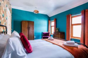 niebieska sypialnia z dużym łóżkiem z czerwonymi poduszkami w obiekcie Gorgeous Victorian house sleeps 6 in Cardiff w Cardiff