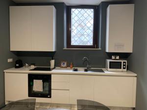 uma cozinha com armários brancos, um lavatório e uma janela em Modern city center apartment em Benevento