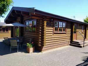 Cabaña de madera con mesa y sombrilla en Osiers Country Lodges, en Diss