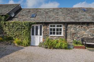 a stone cottage with a white door and a window at Cottage 6 Studio Mews in Keswick