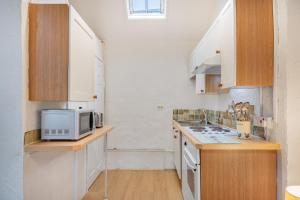 eine kleine Küche mit weißen Schränken und einer Mikrowelle in der Unterkunft Cottage 6 Studio Mews in Keswick