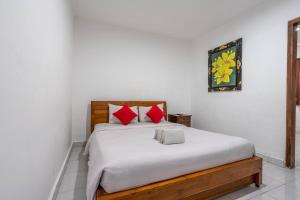 a bedroom with a bed with white sheets and red pillows at Ganandra Stay Denpasar in Denpasar