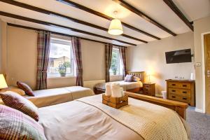 a bedroom with two beds and a tv at Butterchurn Guest House in Otterburn