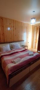 a bedroom with a large bed with wooden walls at dimis ferdobi in Dimi