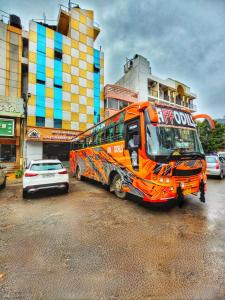 un autobús naranja está estacionado en un estacionamiento en New Jaganmohana Comforts, en Mysore
