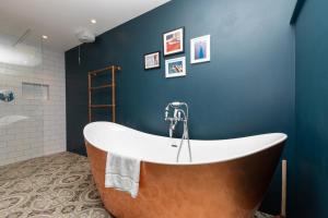 a bath tub in a bathroom with a blue wall at Stylish 2 Bedroom Converted Victorian Storefront in London