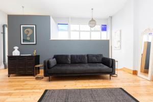 a living room with a black couch and a blue wall at Stylish 2 Bedroom Converted Victorian Storefront in London