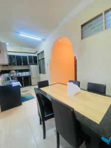 a dining room with a table and chairs and a kitchen at Homestay lagenda padang serai in Padang Serai