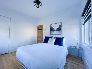 - une chambre blanche avec un grand lit et une fenêtre dans l'établissement Complexe LIVTremblant by Gestion ELITE - LIV4, à Mont-Tremblant