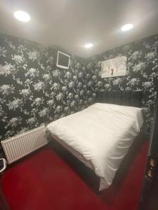 um quarto com uma cama branca e papel de parede floral em Mannbuilding em Londres