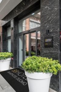 uma entrada para um edifício com dois grandes potes de plantas em BB Hotels Smarthotel Duomo em Milão