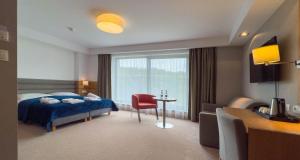 ウストロニエ・モルスキエにあるHotel SKAL Medi SPA & Resortのベッド、テーブル、窓が備わる客室です。