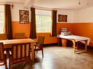 a dining room with orange walls and a table and chairs at Yes Hostel in Fort Portal