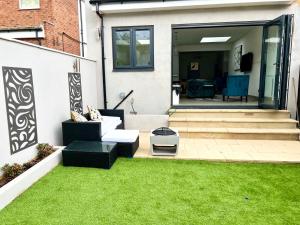 a backyard with a lawn with a white couch and grass at 3 Cosy Homes Walking Distance to Mall with Parking Available to Book Separately 3 Bed House Or 1 Bed Apartment Or Studio in Golders Green