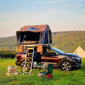 a car parked in a field with a tent on its roof at Scott Rooftop Tent Rental from ElectricExplorers in Hawkshead