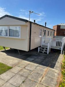 Mobilheim mit einer Veranda und einem weißen Zaun in der Unterkunft Coastfields 3 bed 8 berth holiday home in Ingoldmells