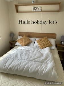 1 cama con edredón blanco y almohadas en Coastfields 3 bed 8 berth holiday home, en Ingoldmells