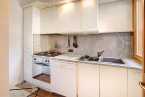 uma cozinha branca com armários brancos e um lavatório em Appartamento Laura em Bormio