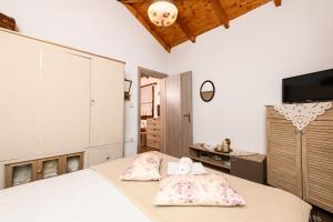 a bedroom with a bed with pillows and a tv at Villa Suzana in Mikros Prinos