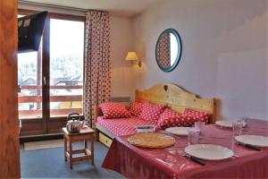 uma sala de estar com uma mesa e um sofá com almofadas vermelhas em RISOUL - Résidence ALTAIR - 5 couchages - À 1min à pieds des pistes em Risoul