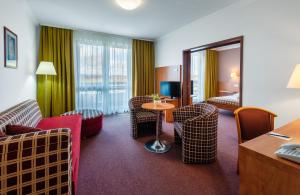 um quarto de hotel com cadeiras, uma mesa e um espelho em Hunguest Hotel Pelion em Tapolca