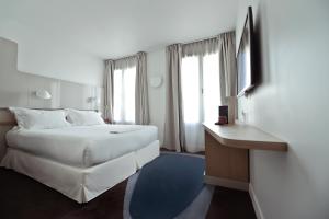 a hotel room with a large white bed and a desk at Hôtel Le Marcel Paris Gare de l'Est in Paris