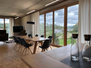 a dining room with a table and chairs and windows at Alb Lodge in Gomadingen