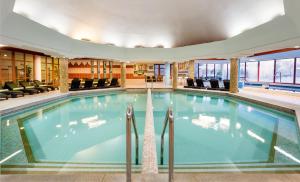 a swimming pool in a hotel lobby with chairs at Hunguest Hotel Pelion in Tapolca