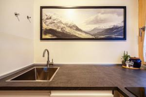 eine Küche mit einem Waschbecken und einem Gemälde an der Wand in der Unterkunft Ferienwohnung Kuppelwies 363 in Ulten