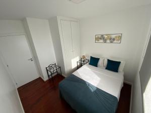 um pequeno quarto com uma cama com almofadas azuis em Apartamento Oliveira no Funchal