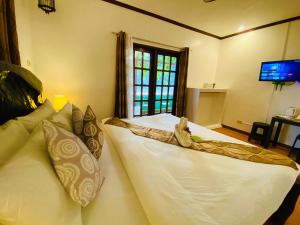 a large white bed in a room with a television at Sophias Beach Guest House in El Nido
