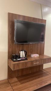 TV de pantalla plana en la parte superior de una estantería de madera en واحة طيبة للشقق الفندقية en Medina