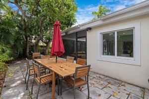 a wooden table with chairs and a red umbrella at Heated Pool I Soundproof Home I Firepit I 630Mbps in Hollywood